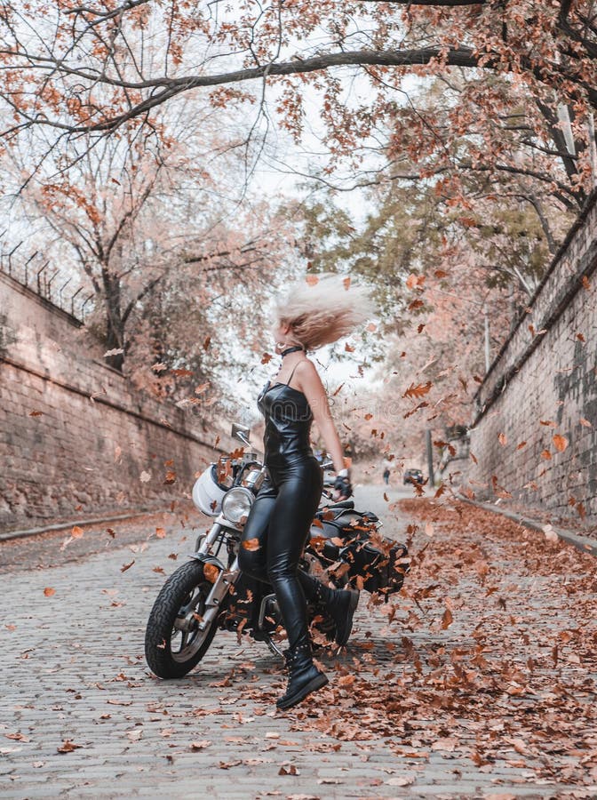 Piękna rowerzysta kobieta pozuje z motocyklem outdoors zdjęcie stock Piękna rowerzysta kobieta pozuje z motocyklem outdoors zdjęcie stock