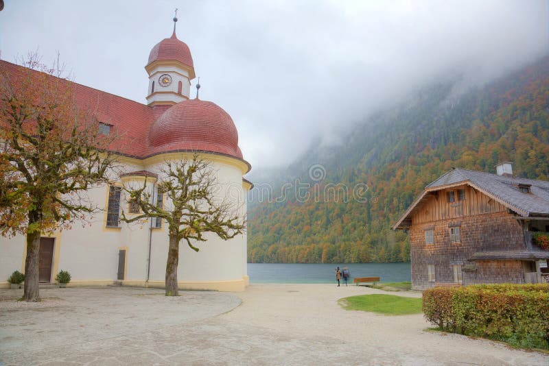 Piękna sceneria Jeziorny Konigssee z sławnym Sankt Bartholomae pielgrzymki kościół jesieni górami w mgłowym i brzeg jeziora zdjęcia stock Piękna sceneria Jeziorny Konigssee z sławnym Sankt Bartholomae pielgrzymki kościół jesieni górami w mgłowym i brzeg jeziora zdjęcia stock
