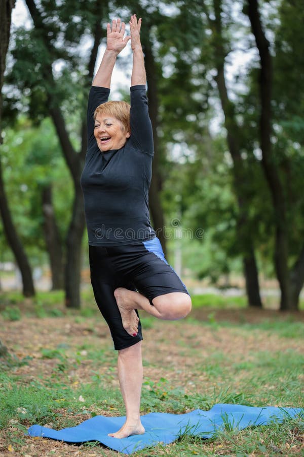 Piękna, szczęśliwa dojrzała kobieta robi joga na parkowym tle, pojęcia gym styl życia ludzie sportów obraz stock Piękna, szczęśliwa dojrzała kobieta robi joga na parkowym tle, pojęcia gym styl życia ludzie sportów obraz stock