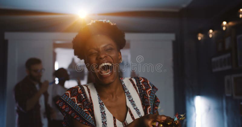 Beautiful happy young African women laughing, blowing on confetti at fun atmospheric celebration party slow motion. Attractive millennial black female student making a wish on her birthday. Beautiful happy young African women laughing, blowing on confetti at fun atmospheric celebration party slow motion. Attractive millennial black female student making a wish on her birthday.