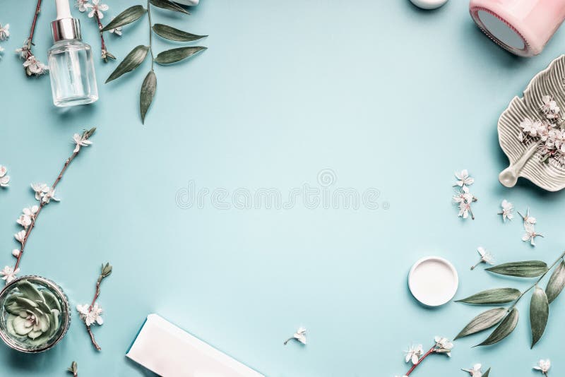 Piękna tło z twarzowymi kosmetycznymi produktami, liśćmi i czereśniowym okwitnięciem na pastelowym błękitnym desktop tle, fotografia stock Piękna tło z twarzowymi kosmetycznymi produktami, liśćmi i czereśniowym okwitnięciem na pastelowym błękitnym desktop tle, fotografia stock