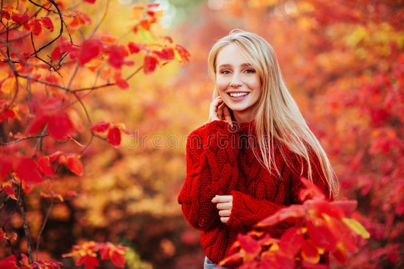 Piękna uśmiechnięta kobieta blisko czerwieni opuszcza outdoors fotografia stock Piękna uśmiechnięta kobieta blisko czerwieni opuszcza outdoors fotografia stock