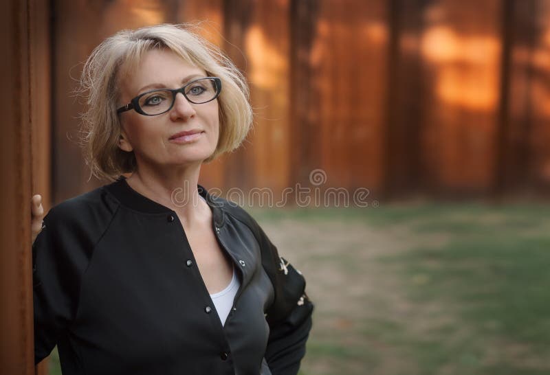 Piękna w średnim wieku kobiety pozycja ścianą w parku Ph zdjęcie stock Piękna w średnim wieku kobiety pozycja ścianą w parku Ph zdjęcie stock