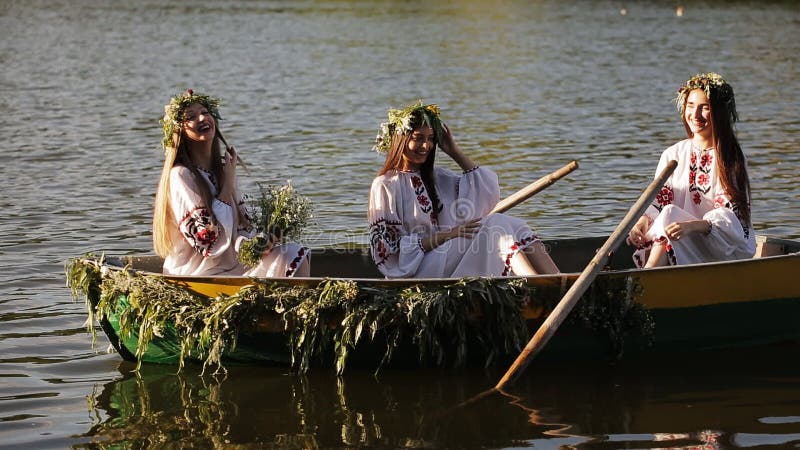 Piękne dziewczyny unosi się na rzece w Slawistycznych upiększonych koszula w łodzi dziewczyna pozuje w wiankach odbicie dalej