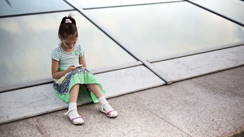 Pięknego dziecka mała dziewczynka cieszy się smartphone