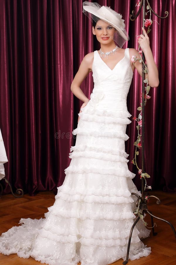 Happy beautiful brunette bride with hat and veil posing, looking at the camera. Happy beautiful brunette bride with hat and veil posing, looking at the camera