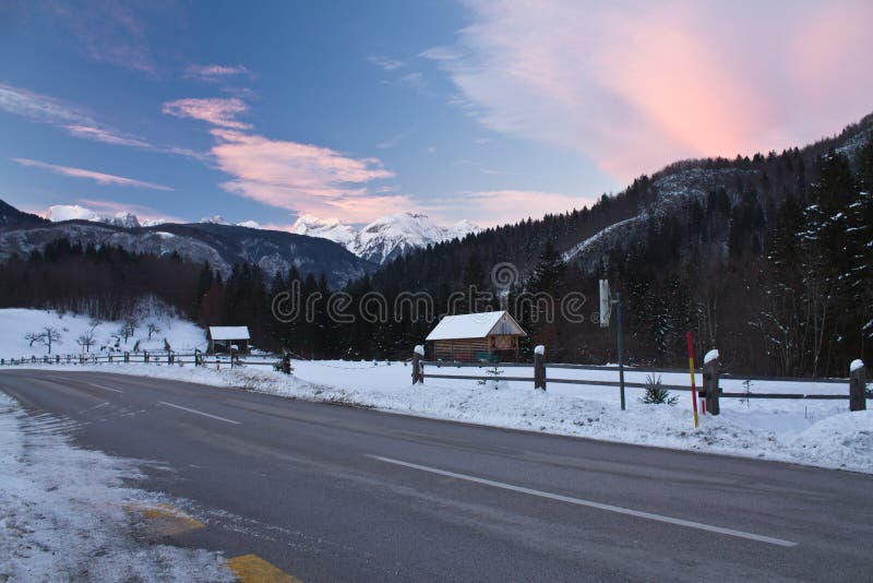 Pięknej wysokogórskiej zimy scenicznej góry pusta droga z śniegiem w kolorowym zmierzchu niebie w julian alps zdjęcia royalty free Pięknej wysokogórskiej zimy scenicznej góry pusta droga z śniegiem w kolorowym zmierzchu niebie w julian alps zdjęcia royalty free