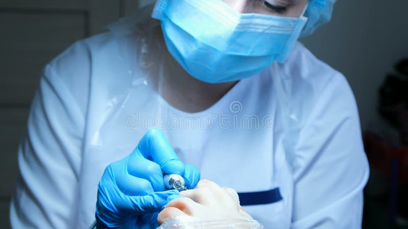 Piękno mistrz trzyma palec u nogi i robi pedicure'owi z maszyną fotografia royalty free Piękno mistrz trzyma palec u nogi i robi pedicure'owi z maszyną fotografia royalty free
