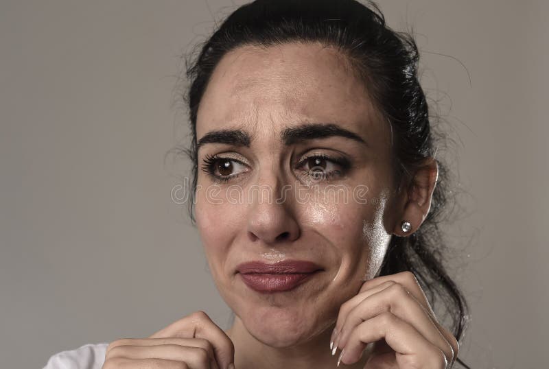 Beautiful face of sad woman crying desperate and depressed with tears on her eyes suffering pain and depression on grey background in sadness facial expression and emotion concept. Beautiful face of sad woman crying desperate and depressed with tears on her eyes suffering pain and depression on grey background in sadness facial expression and emotion concept