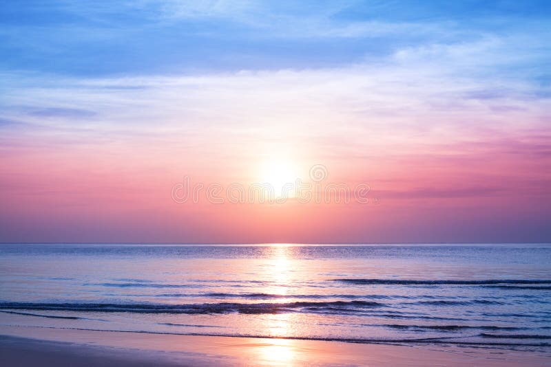 Piękny poranny wschód słońca, błękitne morze, różowe niebo, białe chmury, żółty blask słońca, złota refleksja nad wodą, spokojny