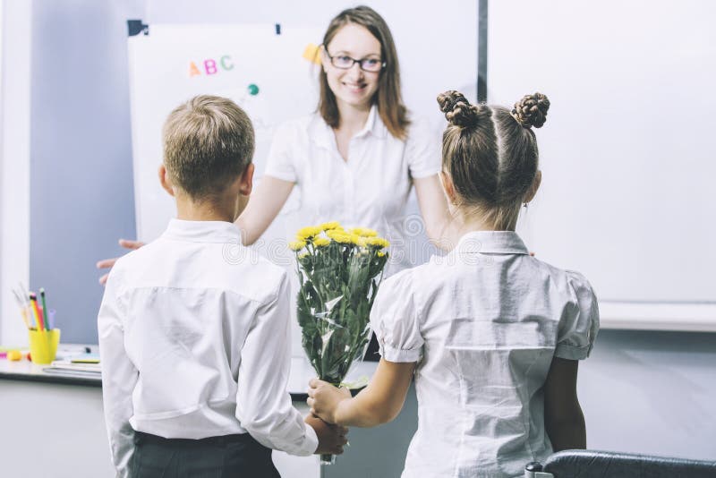 Pięknych dzieci dziecko w wieku szkolnym z kwiatami dla nauczycieli