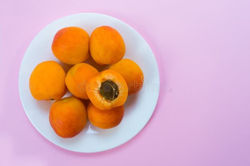 Plaat met rijpe die abrikozen op een roze achtergrond worden geïsoleerd stock afbeelding Plaat met rijpe die abrikozen op een roze achtergrond worden geïsoleerd stock afbeelding