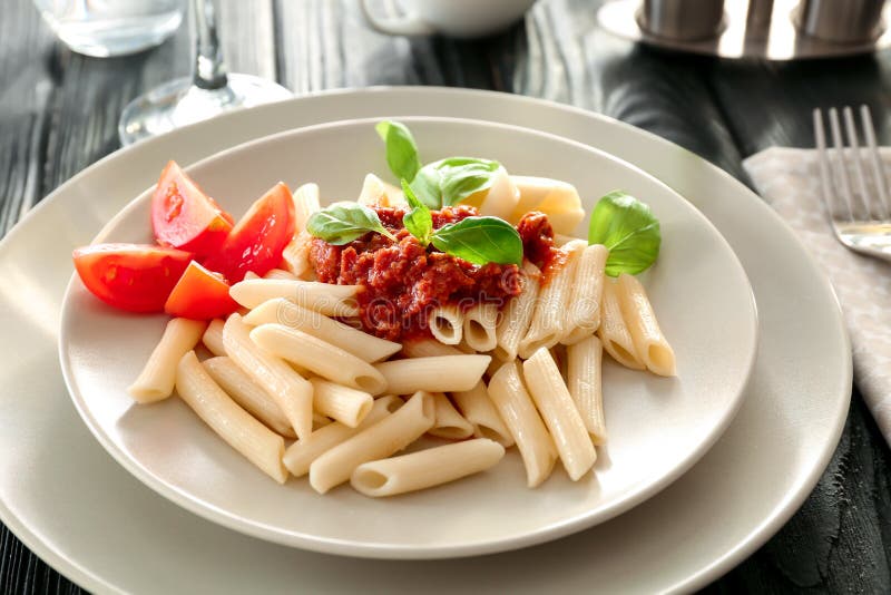 Plaat van smakelijke pennedeegwaren met bolognese saus op lijst stock foto Plaat van smakelijke pennedeegwaren met bolognese saus op lijst stock foto