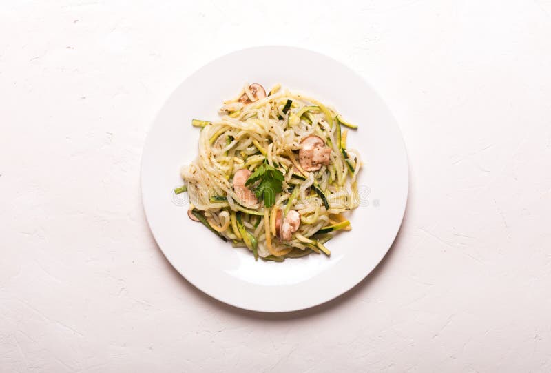 Plaat van spaghetti van courgette en paddestoelsaus op houten lijst wordt voorbereid die stock afbeeldingen Plaat van spaghetti van courgette en paddestoelsaus op houten lijst wordt voorbereid die stock afbeeldingen