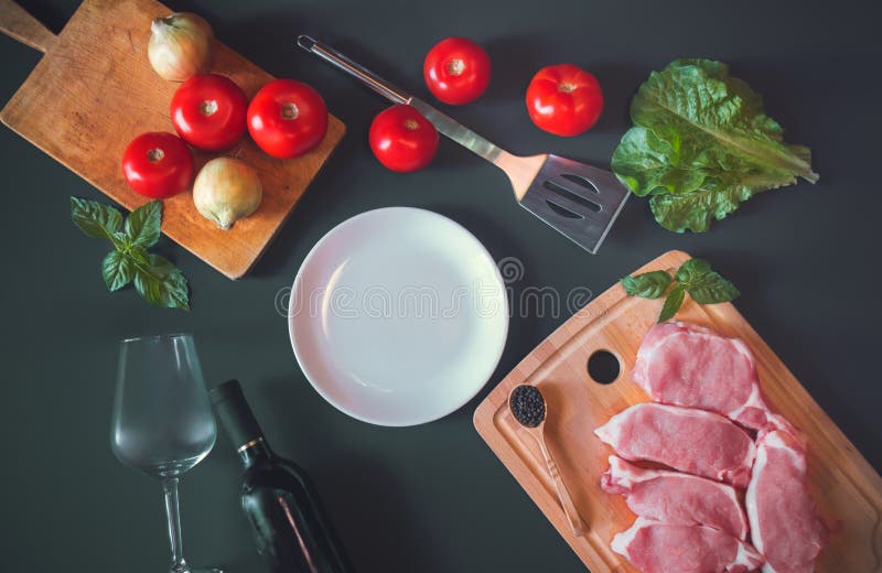 Placa branca como o espaço da cópia, a carne de carne de porco crua fresca, a garrafa do vinho tinto, o vidro de vinho e legumes foto de stock Placa branca como o espaço da cópia, a carne de carne de porco crua fresca, a garrafa do vinho tinto, o vidro de vinho e legumes foto de stock