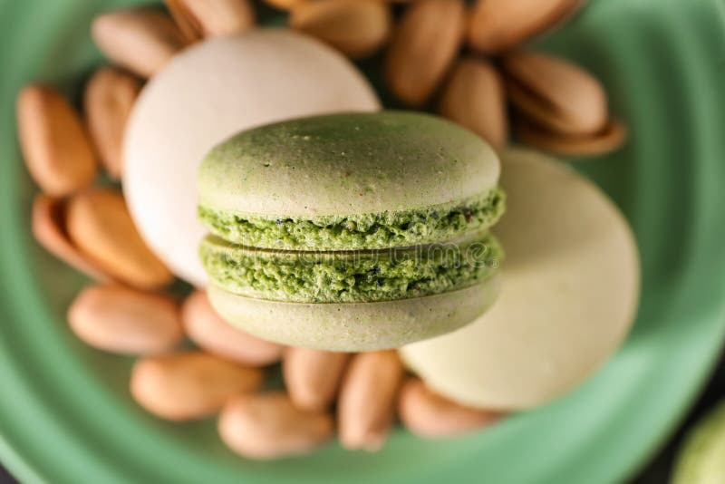 Placa con los macarrones y las nueces de pistacho dulces, primer fotografía de archivo libre de regalías Placa con los macarrones y las nueces de pistacho dulces, primer fotografía de archivo libre de regalías