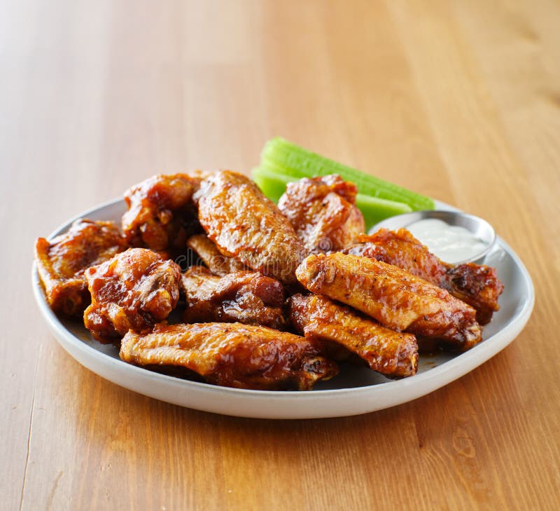 Plate of bbq chicken wings with copy space composition on top of wooden table. Plate of bbq chicken wings with copy space composition on top of wooden table