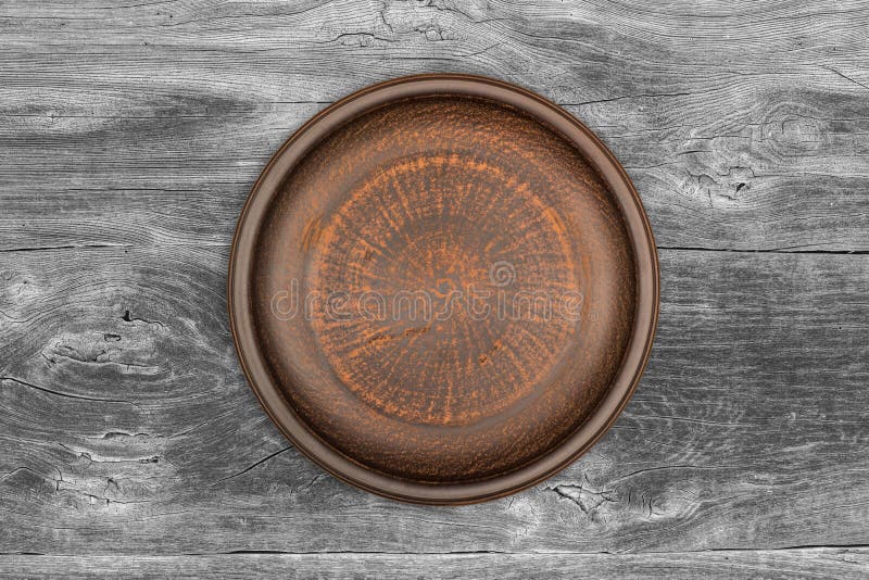 Plato de cerámica marrón vacío sobre un fondo rústico foto de archivo