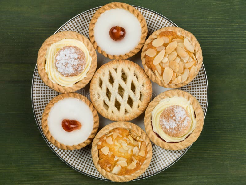 Plate of Assorted Individual Cakes or Tarts Against a Green Background. Plate of Assorted Individual Cakes or Tarts Against a Green Background