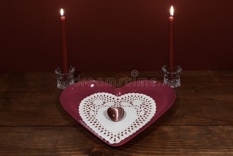 Placa en forma de corazón rosada con el dollie y piedra preciosa, dos velas rojas en los tenedores cristalinos en la tabla de mad fotos de archivo libres de regalías Placa en forma de corazón rosada con el dollie y piedra preciosa, dos velas rojas en los tenedores cristalinos en la tabla de mad fotos de archivo libres de regalías