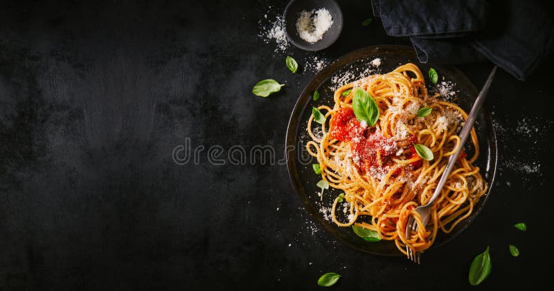 Tasty appetizing classic italian spaghetti pasta with tomato sauce, cheese parmesan and basil on plate on dark table. View from above, horizontal. Tasty appetizing classic italian spaghetti pasta with tomato sauce, cheese parmesan and basil on plate on dark table. View from above, horizontal