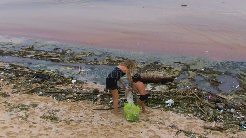 Plage propre de l'océan. Pollution en plastique en tant que problème environnemental. Jeune femme et enfant prenant des déchets et banque de vidéos