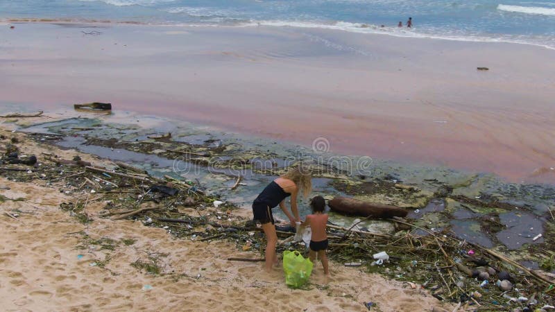 Plage propre. Pollution plastique comme un problème d'environnement. Jeune femme et enfant prenant des déchets et des déchets soli clips vidéos