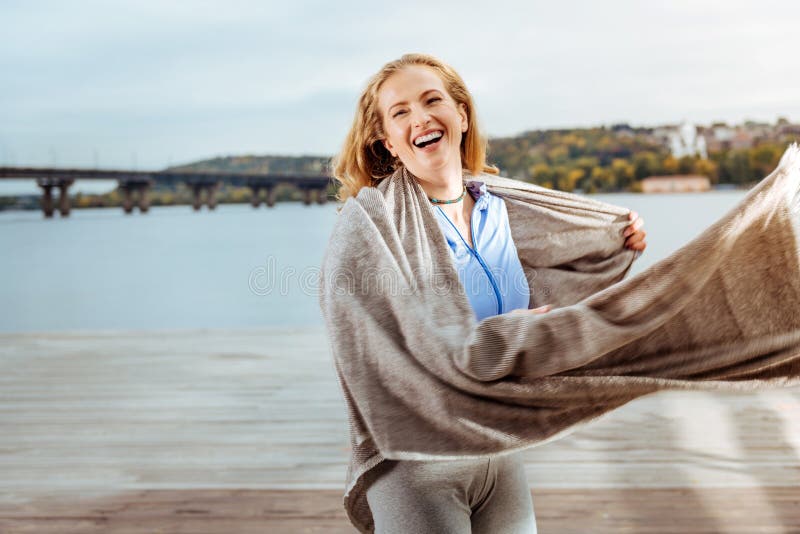 Plaid de port de jeune femme heureuse près de la rivière photographie stock Plaid de port de jeune femme heureuse près de la rivière photographie stock