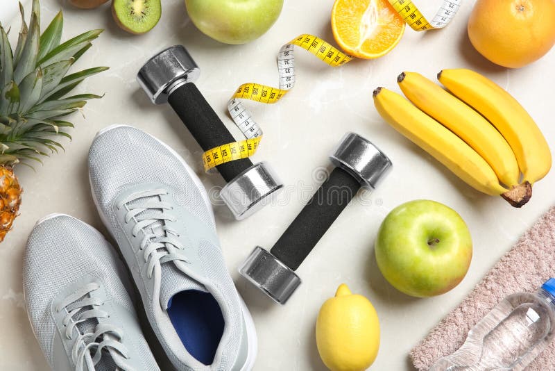 Plan lekmanna- sammansättning med sportobjekt och sund mat på grå bakgrund arkivfoto Plan lekmanna- sammansättning med sportobjekt och sund mat på grå bakgrund arkivfoto