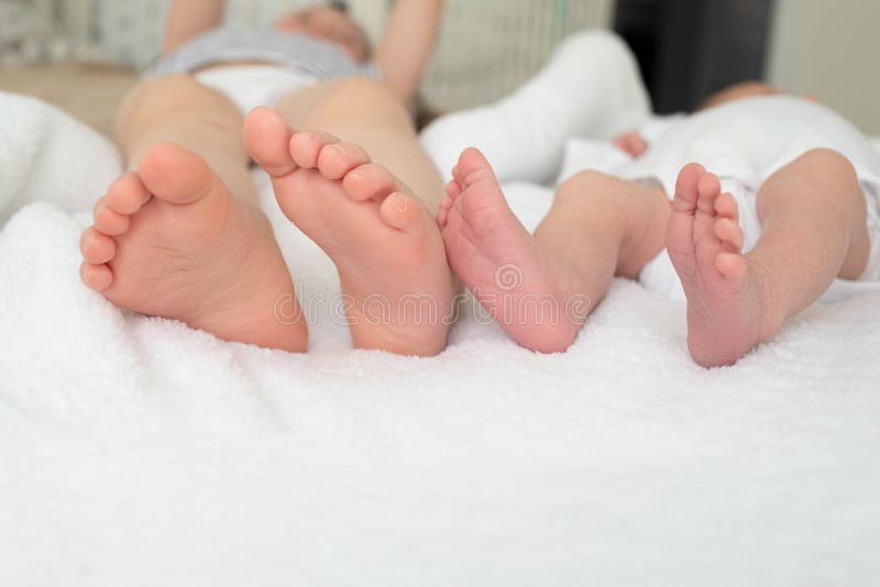 Plan rapproch? de soeurs de Glegs Plan rapproch? de pied de b?b? Les soeurs sont sur le lit photo stock Plan rapproch? de soeurs de Glegs Plan rapproch? de pied de b?b? Les soeurs sont sur le lit photo stock