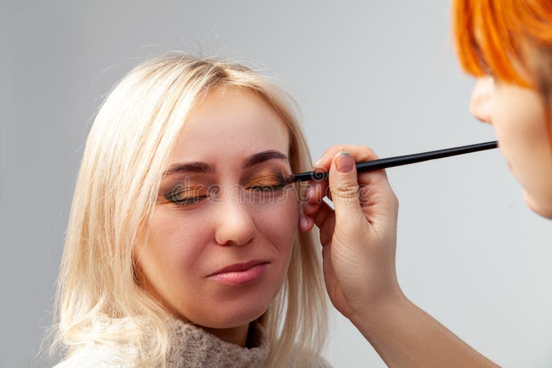 Plan rapproché d'appliquer le maquillage dans le salon sur le modèle dans le style oriental, l'artiste de maquillage mettant les photographie stock libre de droits Plan rapproché d'appliquer le maquillage dans le salon sur le modèle dans le style oriental, l'artiste de maquillage mettant les photographie stock libre de droits