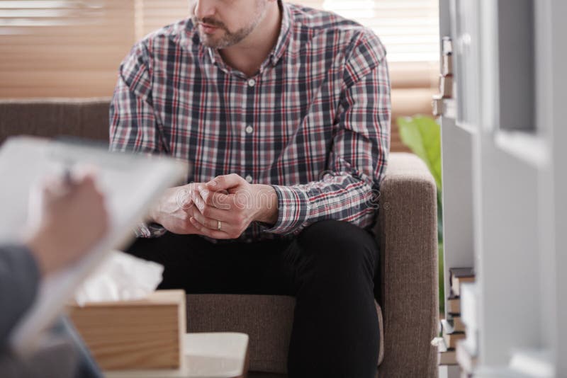 Plan rapproché d'un homme s'asseyant sur un divan pendant la consultation matrimoniale image stock Plan rapproché d'un homme s'asseyant sur un divan pendant la consultation matrimoniale image stock