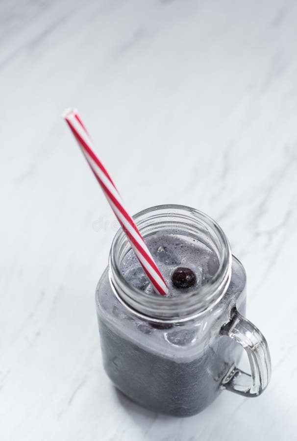 Plan rapproché d'un smoothie de myrtille sur une partie supérieure du comptoir de marbre photographie stock Plan rapproché d'un smoothie de myrtille sur une partie supérieure du comptoir de marbre photographie stock