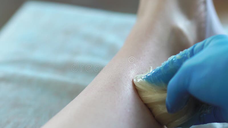 Plan Rapproché Dans Le Maître De Salon De Beauté Dans Les Gants Faisant La Procédure Pour Enlever Les Cheveux Sur Les Jambes Avec Clips Vidéos - Vidéo du soin, retirez: 118301193