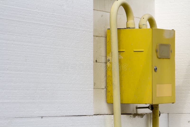 Plan rapproché de boîte jaune de compteur à gaz avec les tuyaux de communication accrochant sur le coin du mur de maison isolé av images stock Plan rapproché de boîte jaune de compteur à gaz avec les tuyaux de communication accrochant sur le coin du mur de maison isolé av images stock
