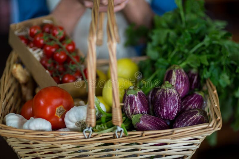 Plan rapproché de personnel féminin tenant le panier des légumes dans la section organique images stock Plan rapproché de personnel féminin tenant le panier des légumes dans la section organique images stock