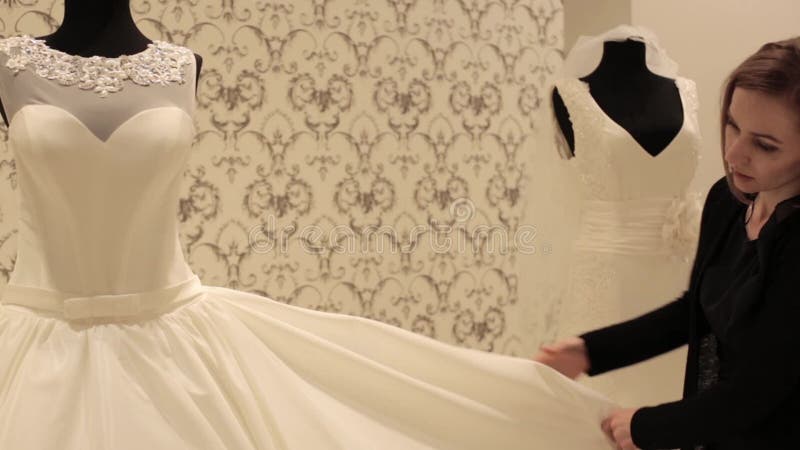 Plan rapproché de simulacre avec la robe de mariage, jeune belle femme choisissant une robe blanche dans une boutique de mariage