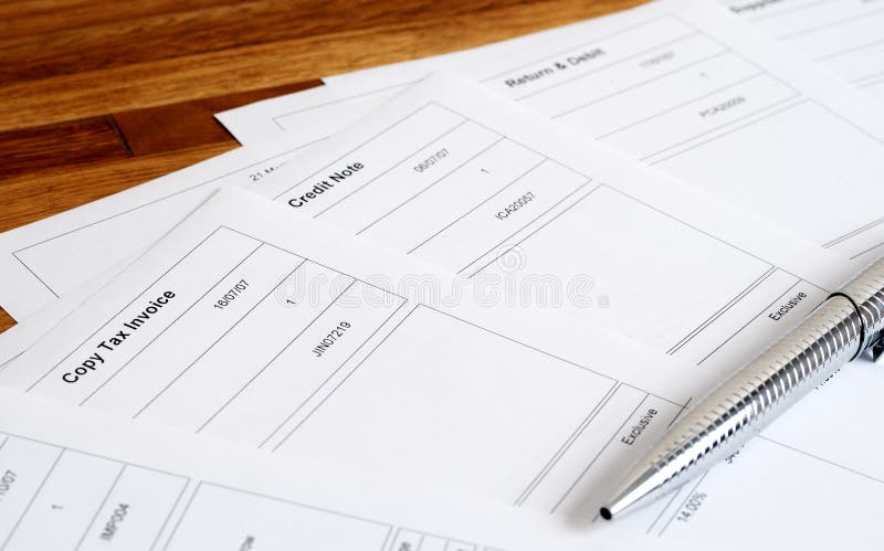 Close-up of business documents including tax invoice, credit note, return and debit with silver pen. Close-up of business documents including tax invoice, credit note, return and debit with silver pen