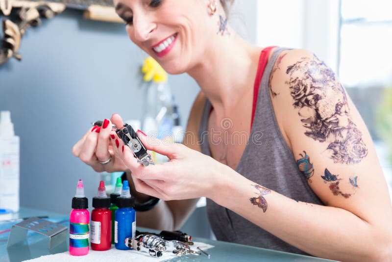 Plan rapproché des mains d'un artiste féminin préparant une machine professionnelle de tatouage image stock Plan rapproché des mains d'un artiste féminin préparant une machine professionnelle de tatouage image stock
