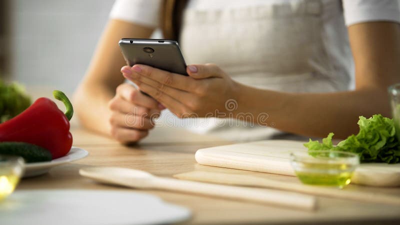 Plan rapproché des mains femelles faisant défiler sur le smartphone, femme choisissant la recette de salade image stock Plan rapproché des mains femelles faisant défiler sur le smartphone, femme choisissant la recette de salade image stock