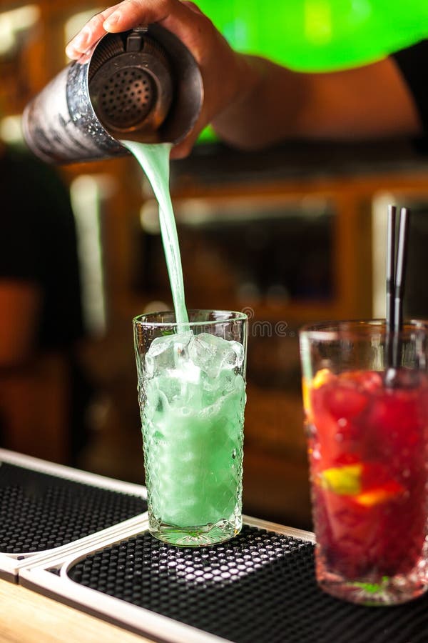 Plan rapproché du barman expert faisant le bleu, la turquoise et les cocktails rouges dans la barre photographie stock libre de droits Plan rapproché du barman expert faisant le bleu, la turquoise et les cocktails rouges dans la barre photographie stock libre de droits