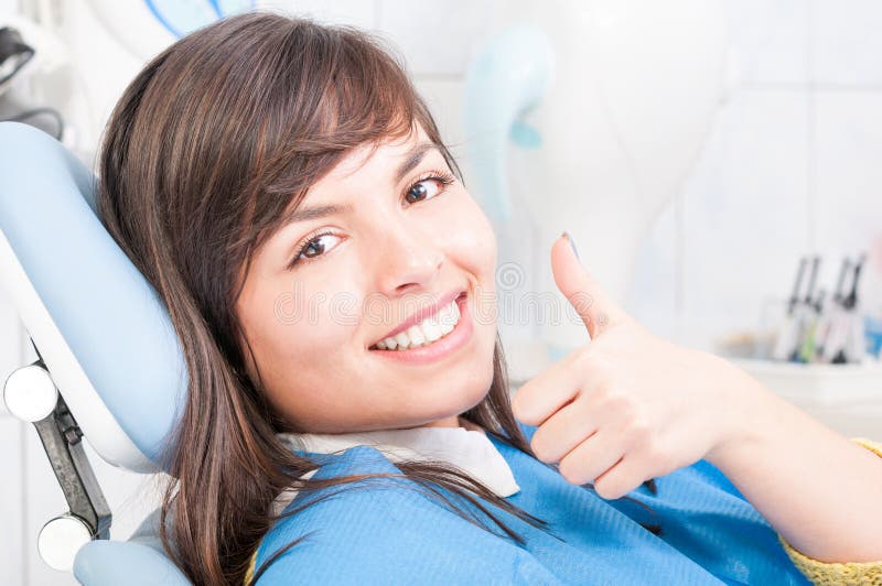 Plan rapproché du patient féminin de brune souriant et montrant le pouce photographie stock Plan rapproché du patient féminin de brune souriant et montrant le pouce photographie stock