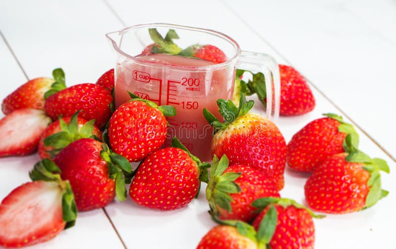 Plan rapproché le jus de fraise et la fraise rouge autour du pot en plastique, sur le panneau de bois de construction image stock Plan rapproché le jus de fraise et la fraise rouge autour du pot en plastique, sur le panneau de bois de construction image stock