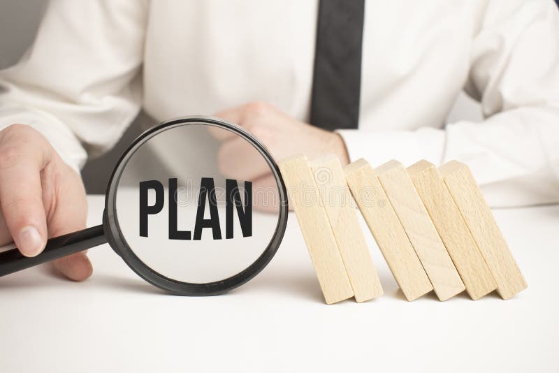 Plan text wooden cube blocks and hand holding magnifying glass on table stock photos