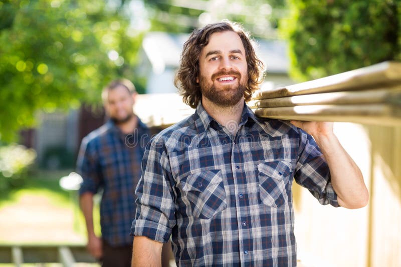 Planches heureuses de With Coworker Carrying de charpentier photographie stock Planches heureuses de With Coworker Carrying de charpentier photographie stock