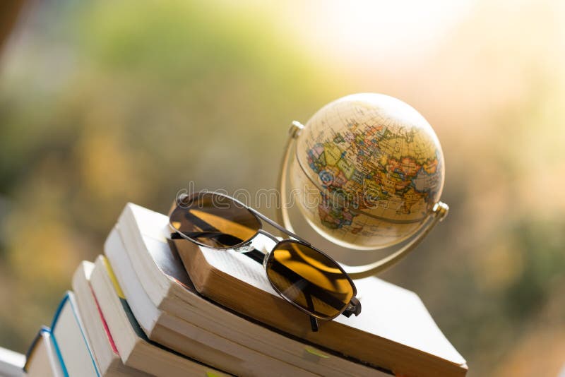 Miniature globe model and sunglasses lying on a stack of books. Symbol for travelling earth transport journey world vacation planning liberty adventure explore trip tourism atlas retro conceptual target country city map navigation lifestyle preparation wanderlust direction horizon global globalisation tourist guide worldwide marketing web wooden voyage blurry cheerful international future. Miniature globe model and sunglasses lying on a stack of books. Symbol for travelling earth transport journey world vacation planning liberty adventure explore trip tourism atlas retro conceptual target country city map navigation lifestyle preparation wanderlust direction horizon global globalisation tourist guide worldwide marketing web wooden voyage blurry cheerful international future