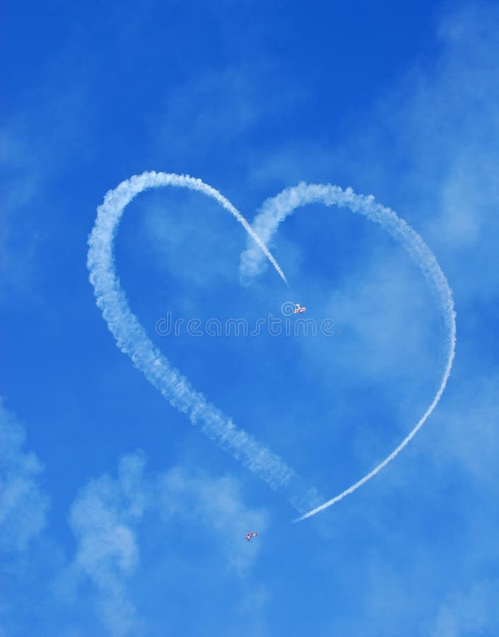 Vintage aircraft with smoke display creating heart shape in sky. Vintage aircraft with smoke display creating heart shape in sky