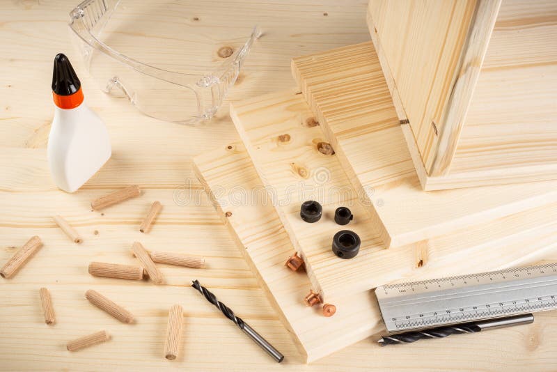 Wooden dowel joint pins drill glue wood planks safety glasses and tools on spruce background. Carpenter industry funiture making concept. Wooden dowel joint pins drill glue wood planks safety glasses and tools on spruce background. Carpenter industry funiture making concept