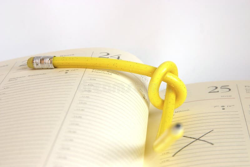 Yellow, twisted pencil on a diary. Yellow, twisted pencil on a diary