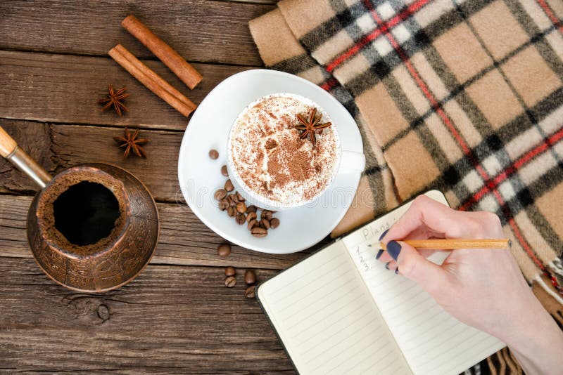 Planning in a cafe. Mug latte, a female hand writing in a notebook with a pencil. Top view stock images Planning in a cafe. Mug latte, a female hand writing in a notebook with a pencil. Top view stock images